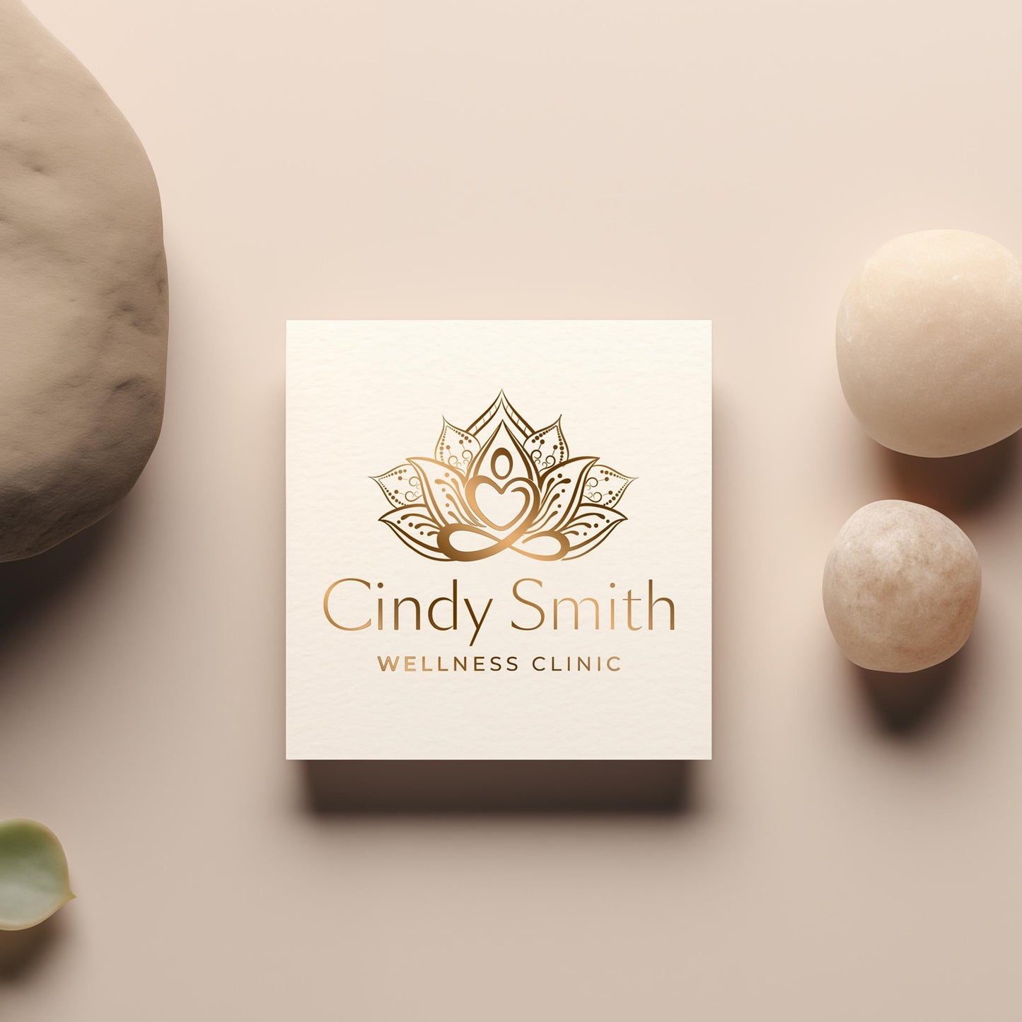 Elegant gold-foil embossed lotus logo on a textured business card, placed on a neutral-toned background with natural stones for a premium brand feel.